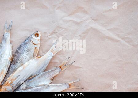 Dried fishes flat lay template banner on craft paper background with empty space for text. Salted roach web cover backdrop. Seafood snack poster, flyer decorative design. Fish frame promotion shop. Stock Photo