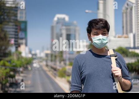Asian man wear surgical face mask carrying  shoulder travel in the city, coronavirus,covid19 Stock Photo