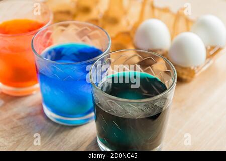 Glass with orange, blue and green paint for Easter eggs. Easter Egg decorating. Stock Photo