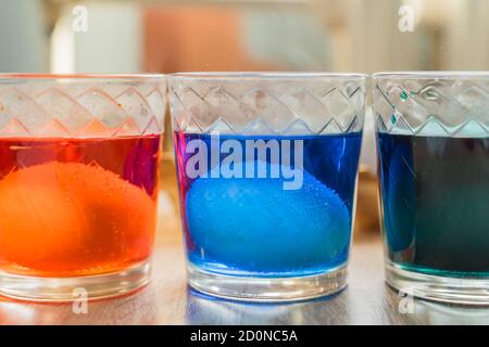 glasses with eggs in multicolored coloring water, close-up. Stock Photo