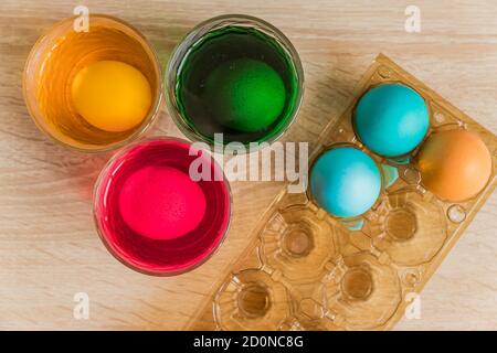Glass with orange, red and green paint for Easter eggs. Easter Egg decorating. Stock Photo