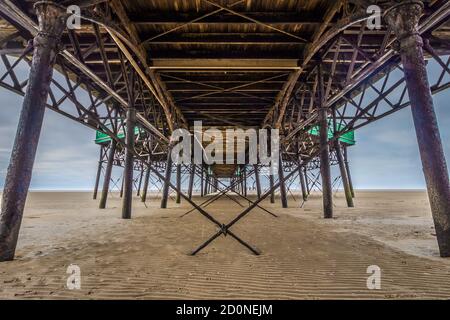 Beneath Lytham St Annes pier on the lancashire coast. Symmetry in the old metal pillars and cables. Stock Photo