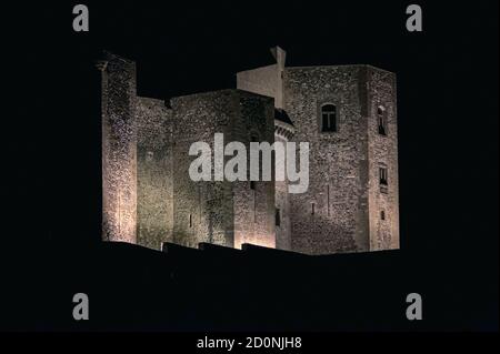 At night, the floodlit walls of the Castello di Melfi dominate views of the ancient town  built on a strategic hilltop below an extinct volcano in Potenza province, Basilicata, Italy.  The castle, once owned by the Houses of Anjou and Aragon, now houses an archaeological museum.  It is one of southern Italy’s strongest medieval fortresses - proved by escaping almost unscathed by violent earthquakes in 1851 and 1930.  It was built as a simple rectangle with square corner towers and further towers defending the main gate.  It now boasts ten towers, seven rectangular and three pentagonal. Stock Photo