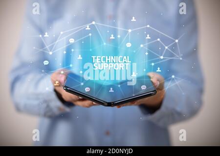 Businessman holding a foldable smartphone with TECHNICAL SUPPORT inscription, new technology concept