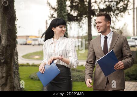 Coworkers walking together and smiling. They are holding folders in their hands. Stock Photo