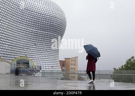 Birmingham, UK. 3rd Oct, 2020. A tourist stands outside the iconic Selfridges building in Birmingham during a spell of heavy rain. Credit: Peter Lopeman/Alamy Live News Stock Photo