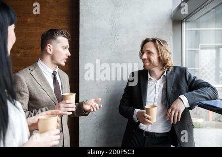 Three colleagues are chatting on a coffe break. One of them is laughing Stock Photo