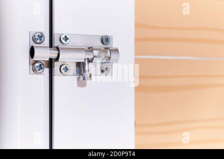 Aluminum manual latch bolt installed on a white lacquered aluminum carpentry door inside a home Stock Photo