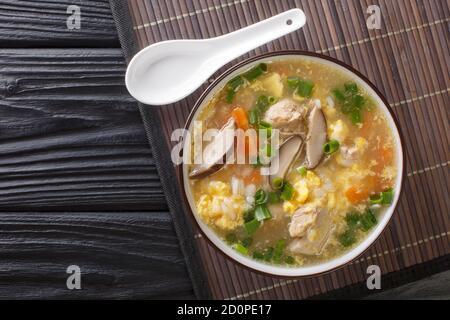 Fragrant Japanese thick rice soup Zosui with egg, mushrooms, vegetables close-up in a bowl on the table. Horizontal top view from above Stock Photo