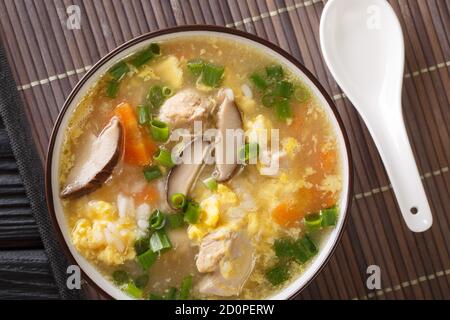 Zosui or ojiya is a mild and thin Japanese winter rice soup with egg, mushrooms, vegetables close-up in a bowl on the table. Horizontal top view from Stock Photo