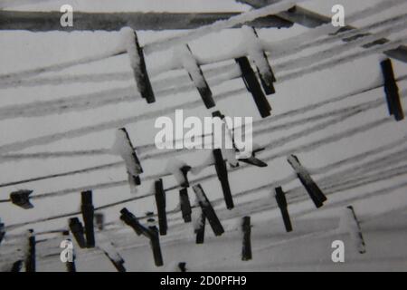Fine 1970s vintage black and white photography of clothes pines hanging on the clothesline covered in snow. Stock Photo