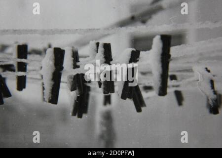 Fine 1970s vintage black and white photography of clothes pines hanging on the clothesline covered in snow. Stock Photo