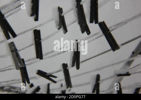 Fine 1970s vintage black and white photography of clothes pines hanging on the clothesline covered in snow. Stock Photo