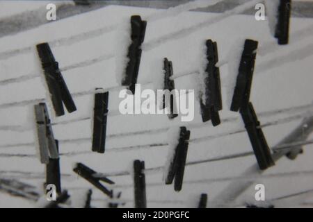 Fine 1970s vintage black and white photography of clothes pines hanging on the clothesline covered in snow. Stock Photo