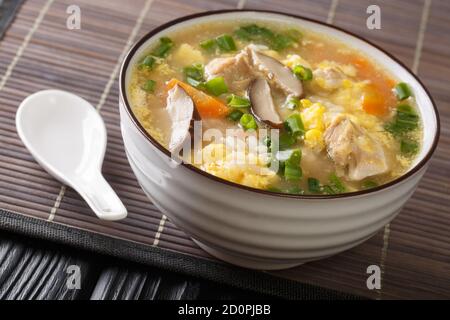 Fragrant Japanese thick rice soup Zosui with egg, mushrooms, vegetables close-up in a bowl on the table. horizontal Stock Photo