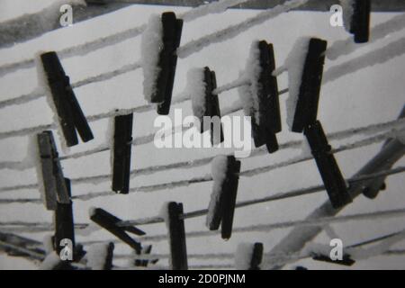 Fine 1970s vintage black and white photography of clothes pines hanging on the clothesline covered in snow. Stock Photo