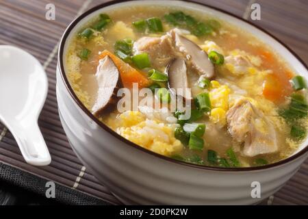 Zosui or ojiya is a mild and thin Japanese winter rice soup with egg, mushrooms, vegetables close-up in a bowl on the table. horizontal Stock Photo