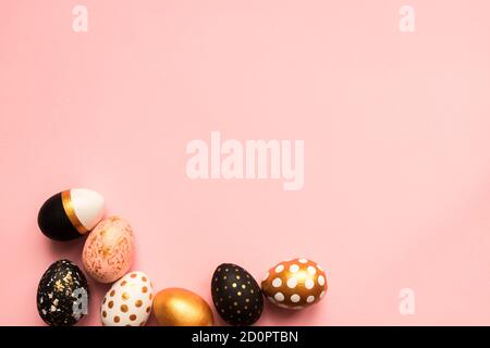 Frame made of wooden painted eggs in gold, black and rose colors on pink background. Happy easter background with copy space Stock Photo