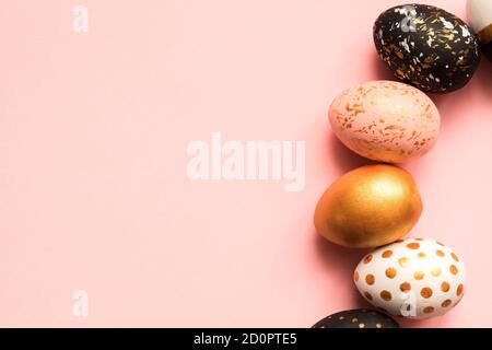 Frame made of wooden painted eggs in gold, black and rose colors on pink background. Happy easter background with copy space Stock Photo