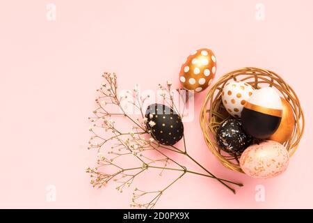 Frame made of wooden painted eggs in gold, black and rose colors on pink background. Happy easter background with copy space Stock Photo