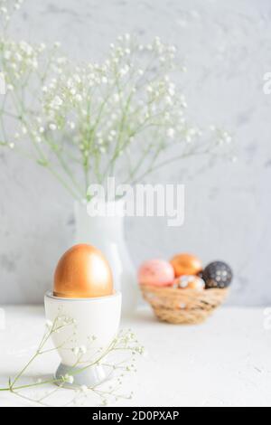 Easter golden eggs and bouquet of gypsophila flowers on the gray wall ...