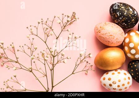 Frame made of wooden painted eggs in gold, black and rose colors on pink background. Happy easter background with copy space Stock Photo