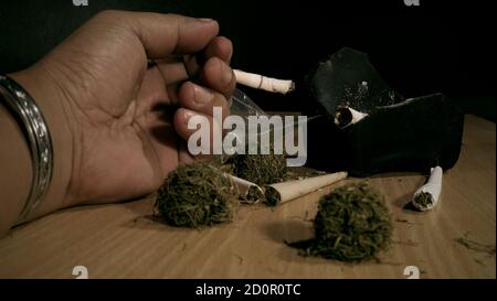 Closeup Hand holding a marijuana joint on the table Stock Photo