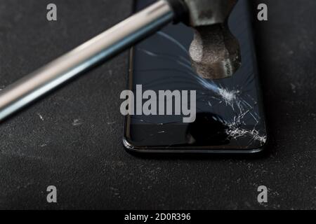 Cell phone with the screen broken by a hammer. close up Stock Photo