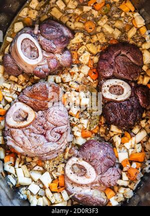 Osso buco in bianco is traditional Italain dish from the Milan area. The veal meat slices with marrow bone are being cooked in a large casserole along Stock Photo