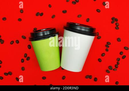 Top view of paper dispocable coffee cups on red background with coffee beans. Stock Photo