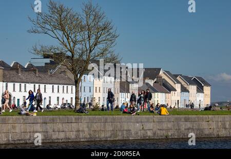 GALWAY CITY, IRELAND - 5th May, 2018: People enjoying a sunny spring day along the bank of Corrib river in the Claddagh area of Galway city, Ireland Stock Photo