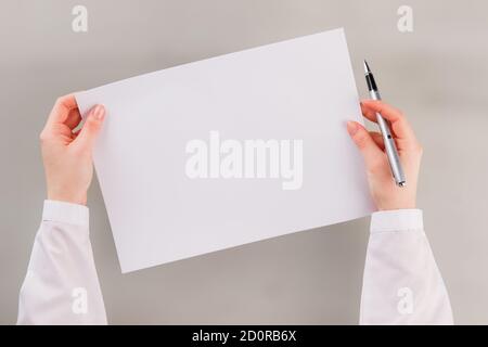 Womans hands holding white blank paper and pen. Stock Photo