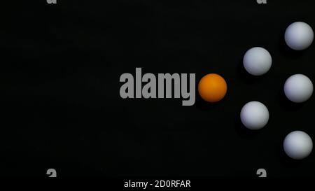 Leadership concept. A triangle form by an orange ball and 5 white ball with black background