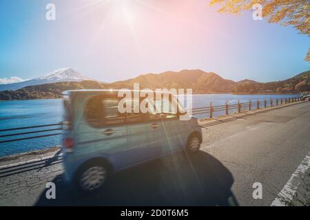 Eco car driving near Mt Fuji in Japan with motion blur showing rapid movement on a highway road at Lake Kawaguchiko. Concept of road trip travel Stock Photo