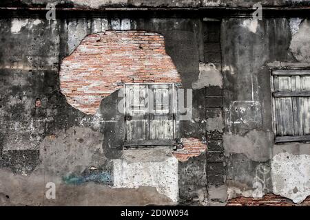 Abandoned brick wall texture of ancient house, abstract rough, cracked, eroded, damaged plaster and old wooden window. Full frame. Stock Photo