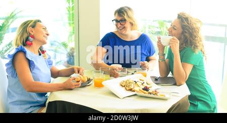 Three girl friends spend time together drinking coffee in the hotel, having fun by breakfast and dessert - Lifestyle bar breakfast concept Stock Photo