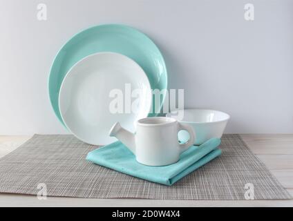 White and turquoise dishes on a woven napkin on a wooden table. Stock Photo