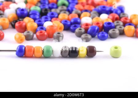 Multi colored Beads spread on white background with needle. Beads with needle . Close up, macro,finishing fashion clothes. make bead necklace, beads f Stock Photo