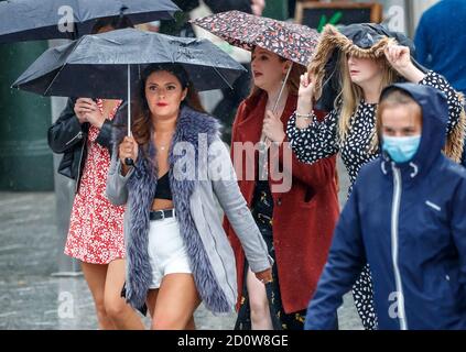 People with umbrellas in Nottingham city centre, as heavy rain is lashing parts of the UK, with the Met Office issuing warnings not seen since March, as winds of up to 65mph are expected along the coast on Saturday along with heavy rain as Storm Alex hits the UK. Stock Photo