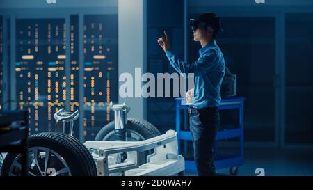 Automotive Engineer Working on Electric Car Chassis Platform, Using Augmented Reality Headset with Touching Gestures. In Innovation Laboratory Stock Photo