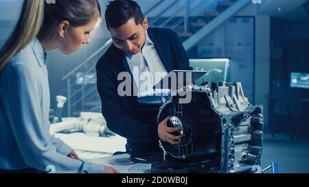 Development Laboratory Room with Professional Automotive Design Engineer Working on a Electric Car Gear Transmission. Chassis with Wheels, Batteries Stock Photo
