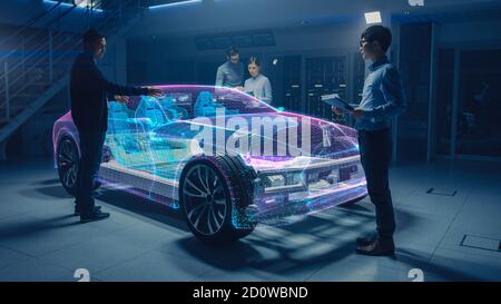 Group of Automobile Design Engineers Working on Augmented Reality 3D Model Prototype of Electric Car Chassis. Automotive Innovation Facility: 3D Stock Photo