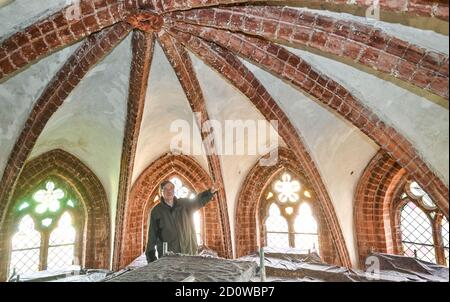 Eberswalde, Germany. 28th Sep, 2020. Hanns-Peter Giering, pastor, stands on scaffolding under the vaulted ceiling of the medieval Maria Magdalenen Church. A smouldering fire was discovered in the church before the fire could destroy the valuable wooden inventory. Nevertheless, a thick layer of soot covered the organ, altar, ceiling frescos and pulpit, which has been removed for months. Credit: Patrick Pleul/dpa-Zentralbild/ZB/dpa/Alamy Live News Stock Photo