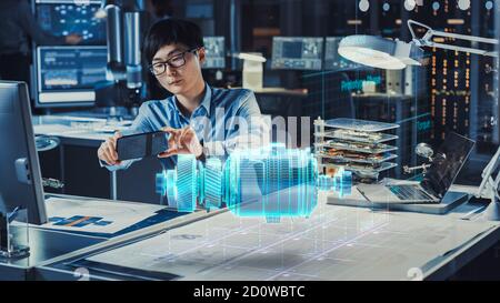 Industrial Engineer Works with Smartphone Using Augmented Reality Holographic Projection 3D Model of the Enlectric Motor Prototype. Development of Stock Photo