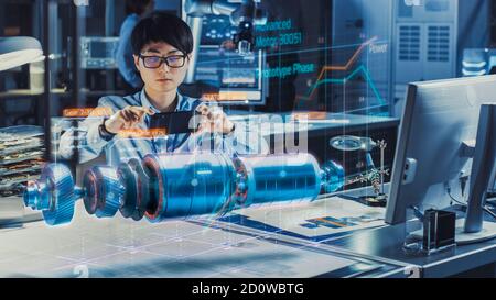 Industrial Engineer Works with Smartphone Using Augmented Reality Holographic Projection 3D Model of the Electric Motor Prototype. Development of Stock Photo