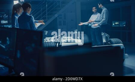 Automobile Engineers Working on Electric Car Chassis Platform, Using Tablet Computer Augmented Reality with CAD Software for 3D Concept. In Automotive Stock Photo