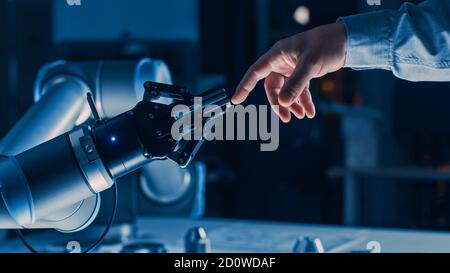 Futuristic Robot Arm Touches Human Hand in Humanity and Artificial Intelligence Unifying Gesture. Conscious Technology Meets Humanity. Concept Stock Photo