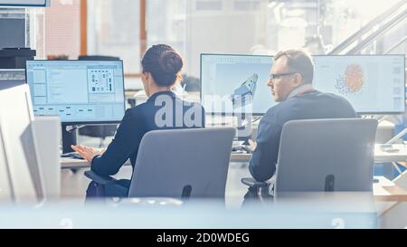 Back View of Team of Technology Engineers Working on Desktop Computers in Office. Screens Show IDE / CAD Software, Implementation of Machine Learning Stock Photo