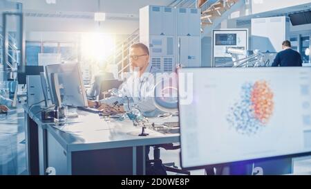 Electronics Design Engineer Working with Circuit Boards, Doing Maintenance and Soldering Motherboard Components. Screen Shows Neural Network, Machine Stock Photo