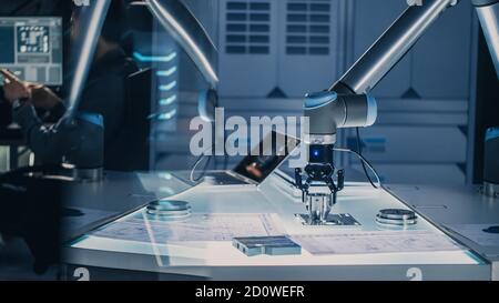 Futuristic Artificial Intelligence Robotic Arm Operates and Moves a Metal Object, Picks It Up or Puts it Down. High Tech Research Laboratory with Stock Photo